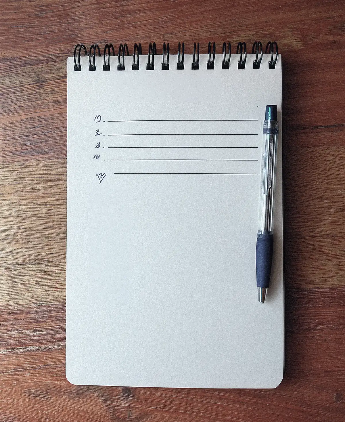 Cuaderno con una lista de tareas escrita a mano junto a una lupa sobre papel impreso