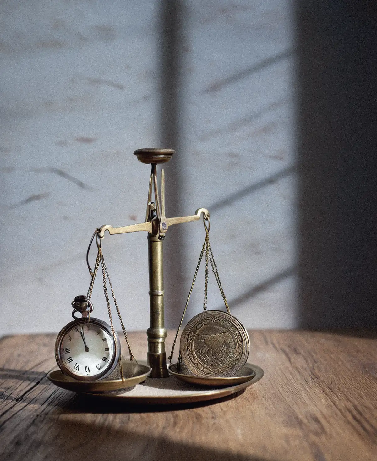Balanza antigua de dos platillos con un reloj de bolsillo en uno y una moneda en el otro