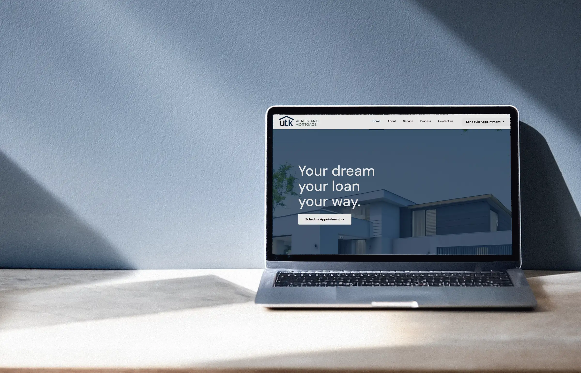 Web de UTK Realty and Mortgage abierta en un portátil junto a la pantalla de reserva de cita
